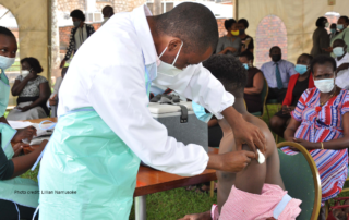A health worker administering a vaccine at an Amref Uganda vaccination site