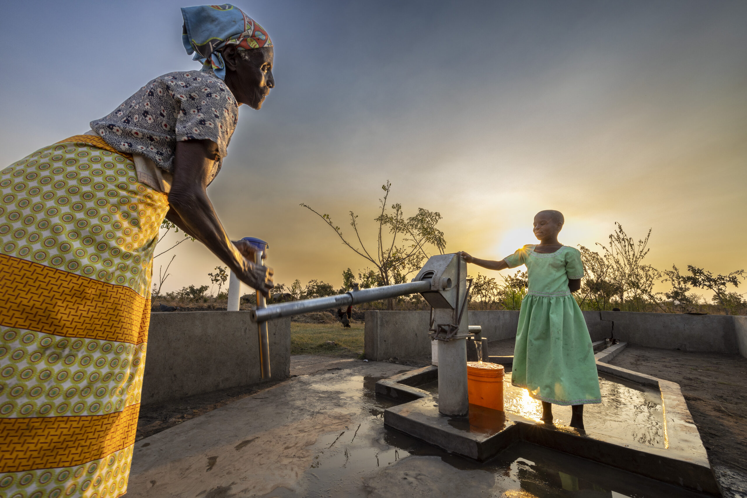 Elistina and her granddaughter at the Amref borehole as the sunsets